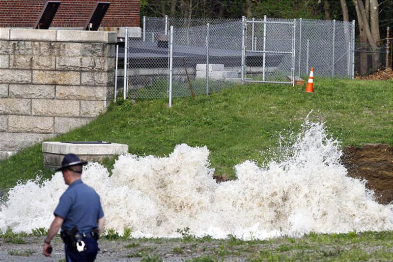 Drinking water surges from the ground at the site of a water main break in Weston, Mass., on Saturday.