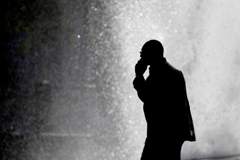 In this Thursday, Oct. 11, 2012 file photo, a pedestrian talking on a cellphone is silhouetted in front of a fountain in Philadelphia.