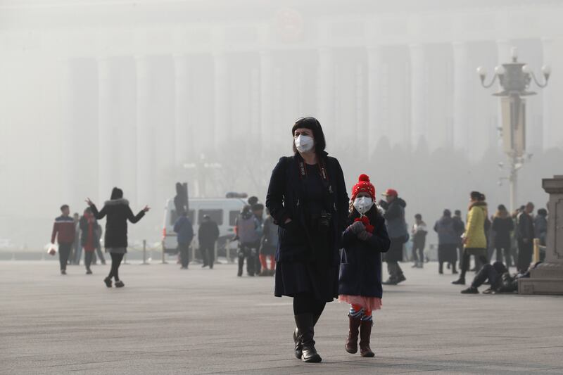 A foreign tourist and a child wearing protection masks walk through Tiananmen Square in Beijing as the capital of China is blanked by heavy smog on Wednesday, Jan. 4, 2017. China has long faced some of the worst air pollution in the world, blamed on its r