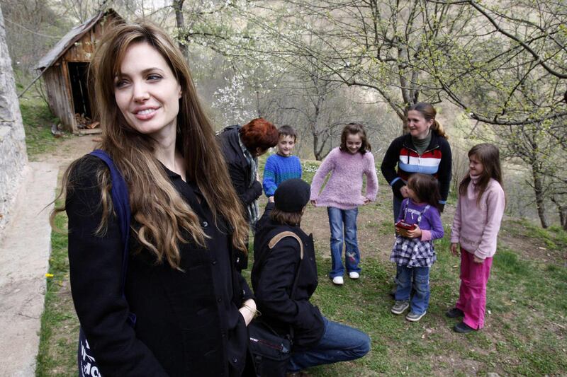 UNHCR goodwill ambassador Angelina Jolie, left, and Brad Pitt, second from left in foreground, visit Bosnian Muslim refugee Sabina Karman, second from left in background, and her four children, in the village of Medjedja, near the eastern Bosnian town of