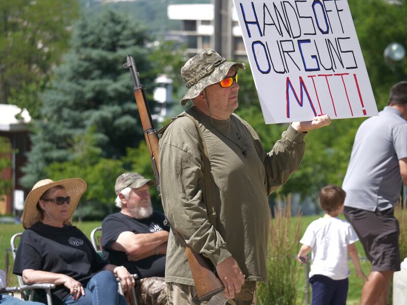 Steve Jensen looks on as he holds a sign reading, “Hands off our guns Mitt,” during a Second Amendment rally.