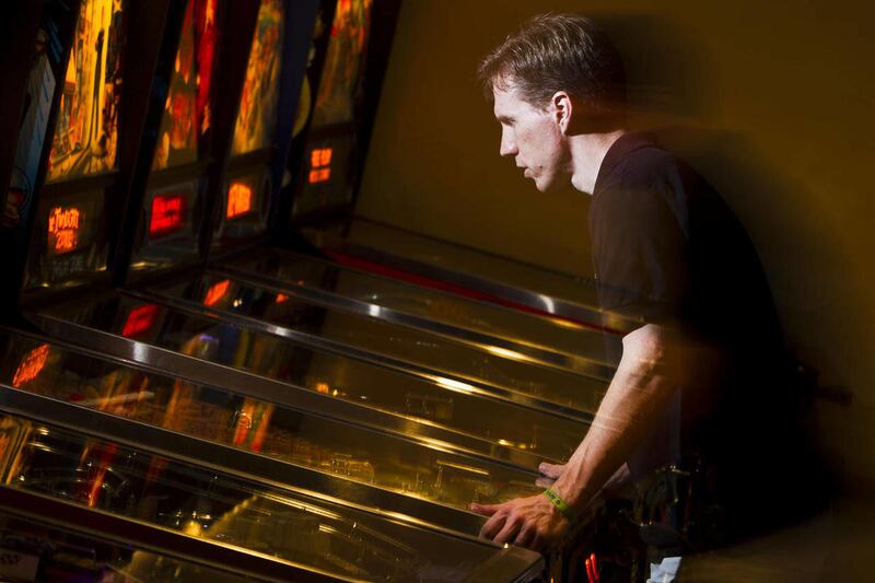 In this July 11, 2011 photo, Mark Pearson, president of the Arizona Pinball Players League, plays the 1993 version of Indiana Jones Pinball Adventure in his basement pinball arcade in Phoenix. Pearson, 41, a Phoenix pharmacist with 19 pinball machines in
