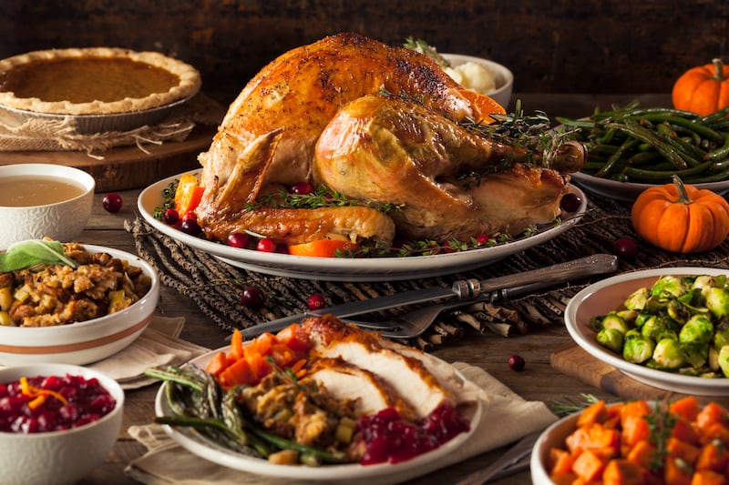 A Thanksgiving dinner on a table, including a roasted turkey, pumpkin pie and stuffing.