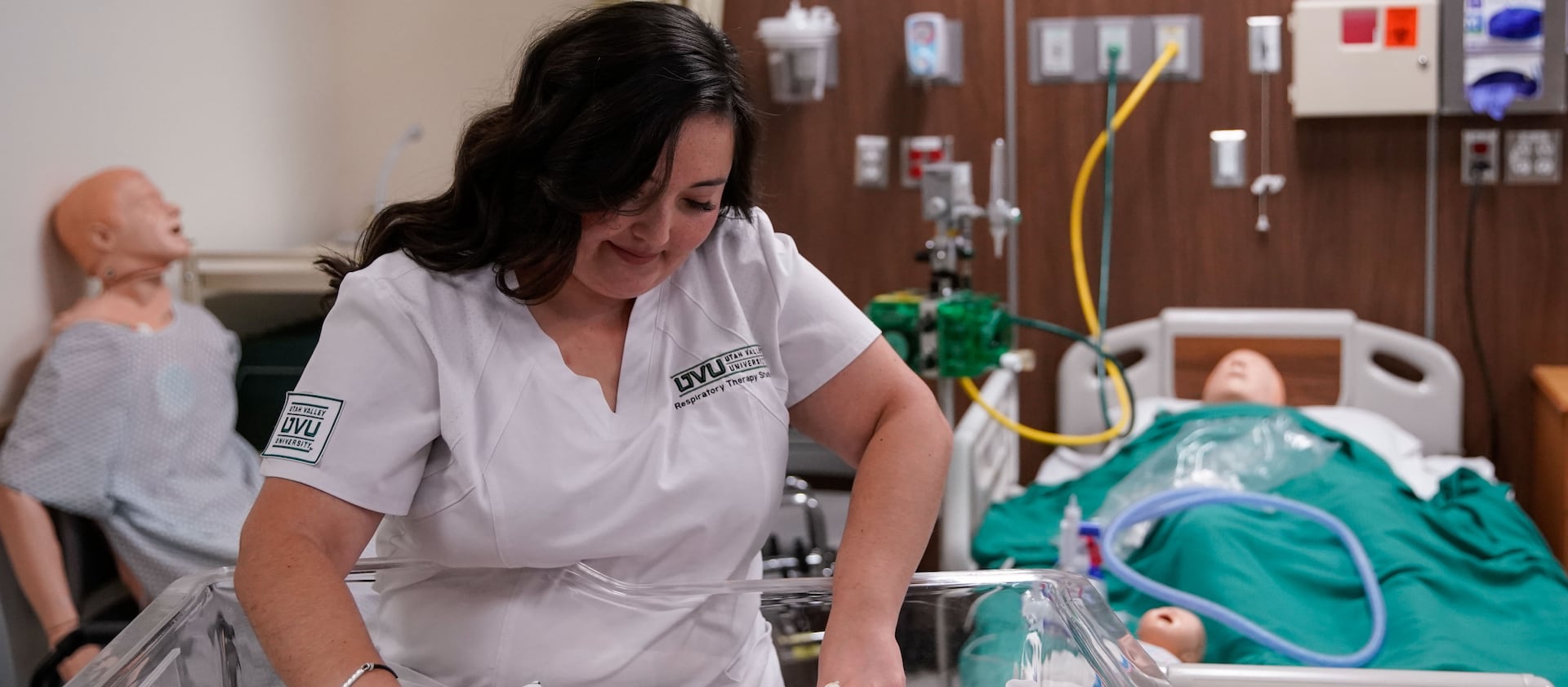 Dominique Elder prepares a mannequin to practice nasal continuous positive airway pressure therapy.