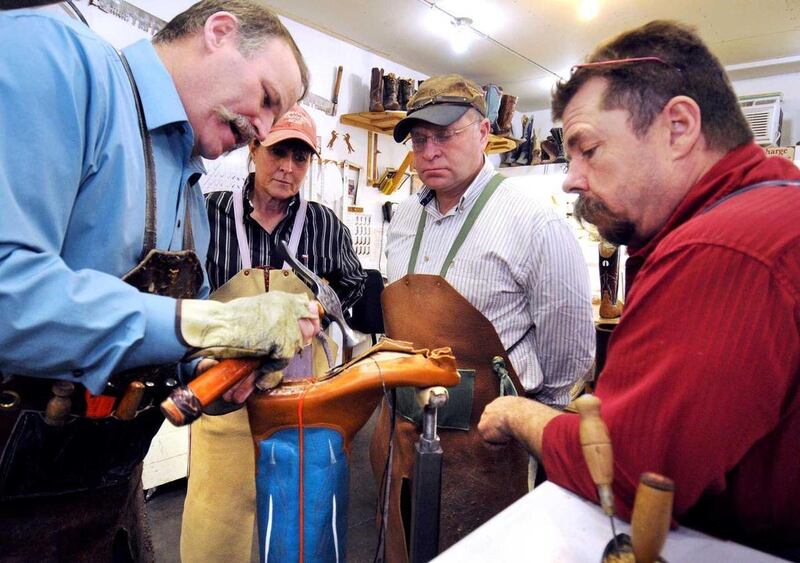 In this March 28, 2012 photo, master boot maker Dan Schwarz, left, demonstrates how to welt a boot for students, from second left, Nicol Hatch, Troy James and Bob Bugeaud, during boot making school at his shop in Dillon, Mont. Schwarz and his family not o