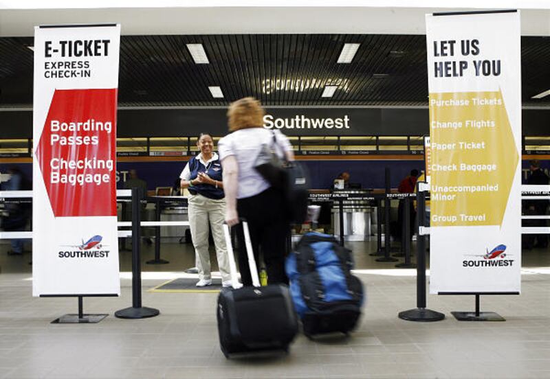 A Southwest Airlines ticket agent greets a passenger near the airline’s check-in line at Los Angeles International Airport.