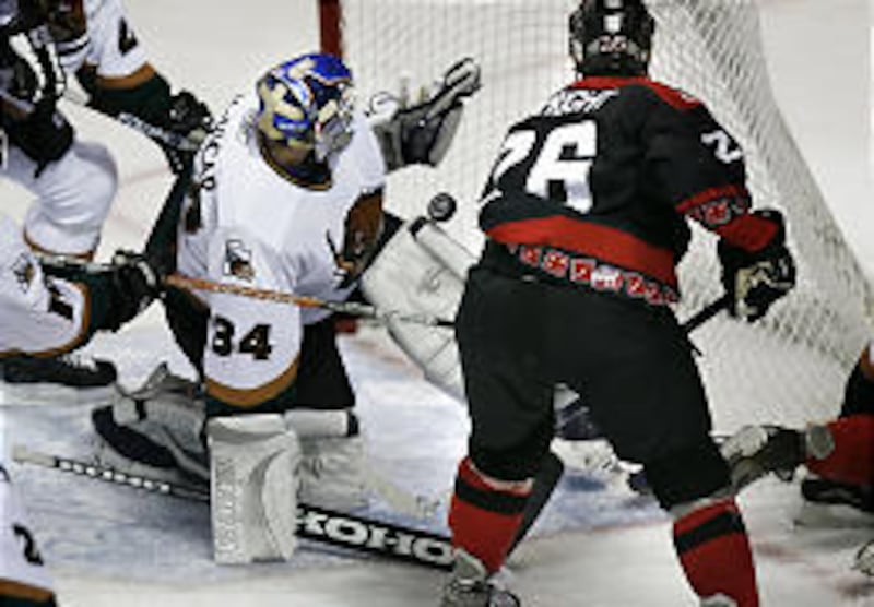 Grizzlies goalie Rob McVicar (34) can't quite grab the puck as Wrangler's Shawn Limpright (26) attacks in Utah's home-opener Friday against Las Vegas. The Wrangers' spoiled the opener at the E Center with a 3-2 shootout victory.