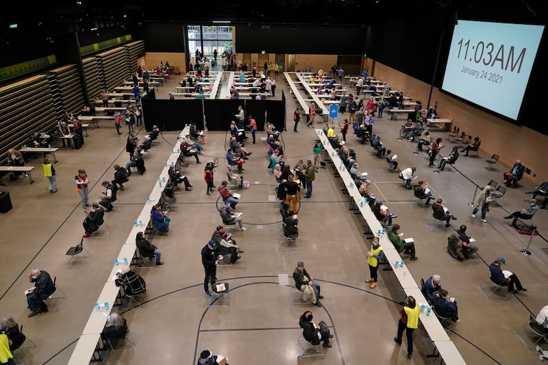 People are given the first of two doses of the Pfizer vaccine for COVID-19, Sunday, Jan. 24, 2021, at a one-day vaccination clinic set up in an Amazon.com facility in Seattle and operated by Virginia Mason Franciscan Health. A Washington state hospital has apologized for asking benefactors to sign up for COVID-19 vaccine distribution.