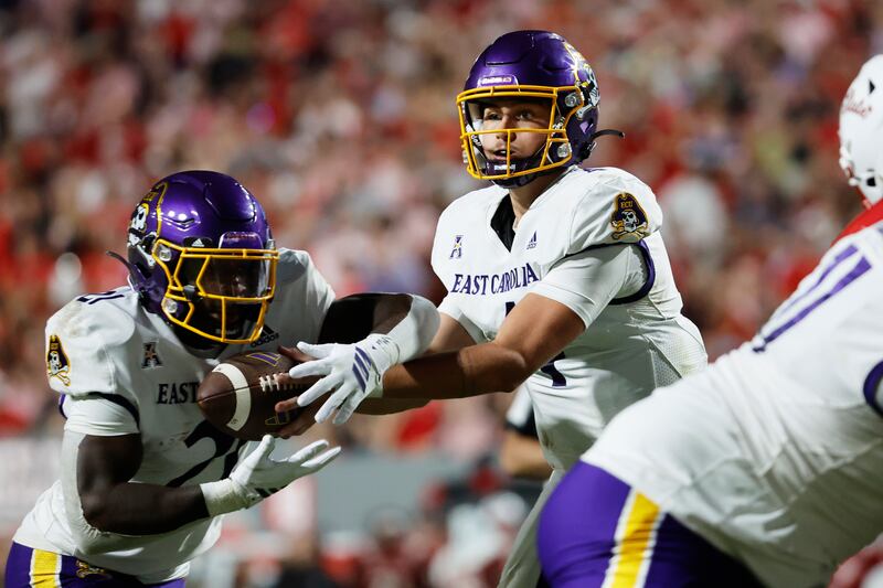 East Carolina quarterback Katin Houser, center, hands off the ball to running back Marlon Gunn Jr. during game against North Carolina State in Raleigh, N.C., Thursday, Aug. 28, 2025.