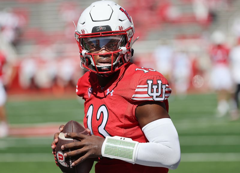 Utah Utes quarterback Nate Johnson (wearing red) warms up.