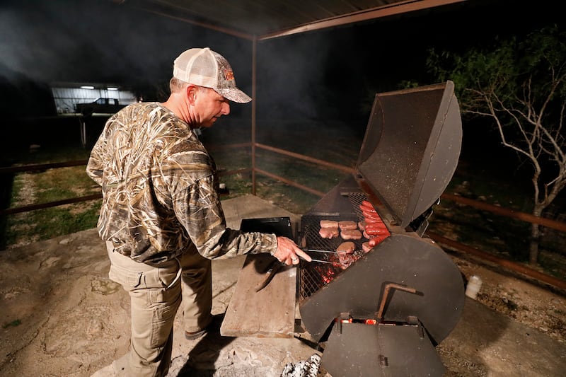 Ty Detmer barbecues sausage and venison steaks wrapped in bacon on his T14 Ranch Thursday, Nov. 15, 2018, near Freer, Texas.
