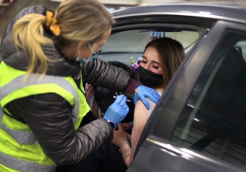 Jennifer Okutani receives her booster shot from Addy Aven at the drive-thru COVID-19 vaccination clinic in Farmington.