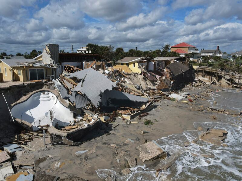 Homes are damaged and collapsed after the shore on which they stood was swept away following the passage of Hurricane Nicole.