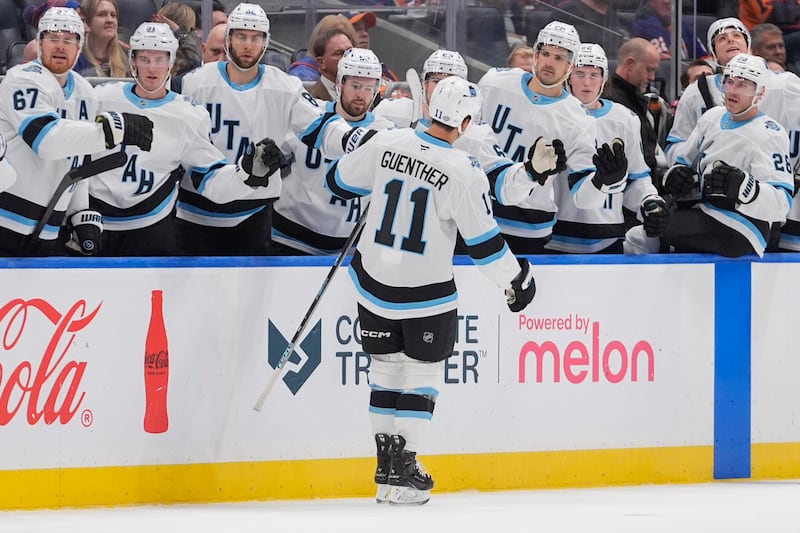 Utah Hockey Club's Dylan Guenther (11) celebrates with teammates after scoring during the third period of an NHL hockey game against the New York Islanders Thursday, Oct. 10, 2024, in Elmont, N.Y.