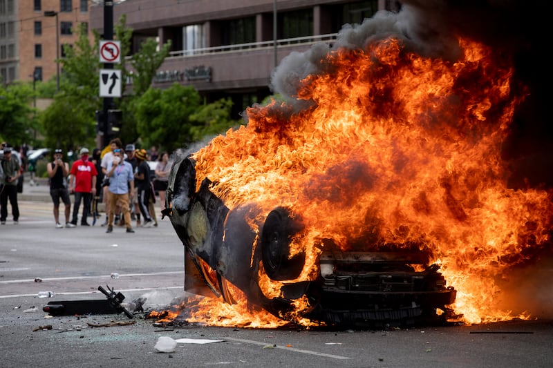 A police car is engulfed in flames as people protest police brutality in Salt Lake City on Saturday, May 30, 2020. Protesters joined others across the nation to decry the death of George Floyd, a black man , who died while being taken into custody by police in Minneapolis earlier this week. Video showed an officer kneeling on his neck while he implored, “I can’t breathe.”