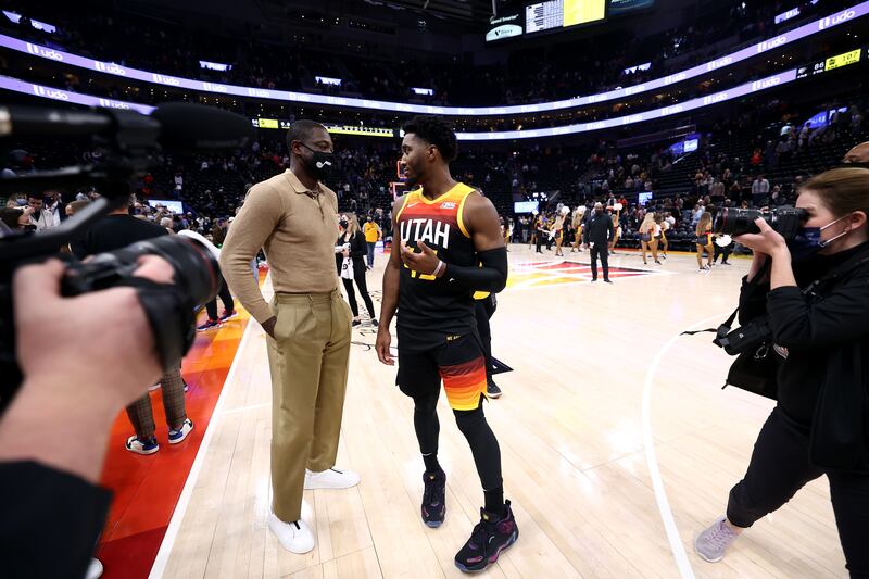 Utah Jazz part owner Dwyane Wade, wearing a suit, talks with Utah Jazz guard Donovan Mitchell