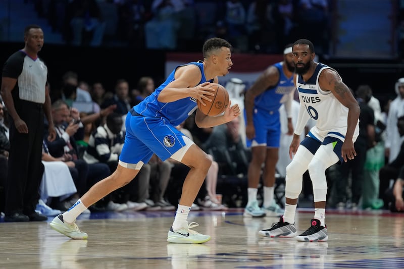 Dante Exum of Dallas Mavericks drives by Mike Conley of Minnesota during a preseason game between Dallas Mavericks.