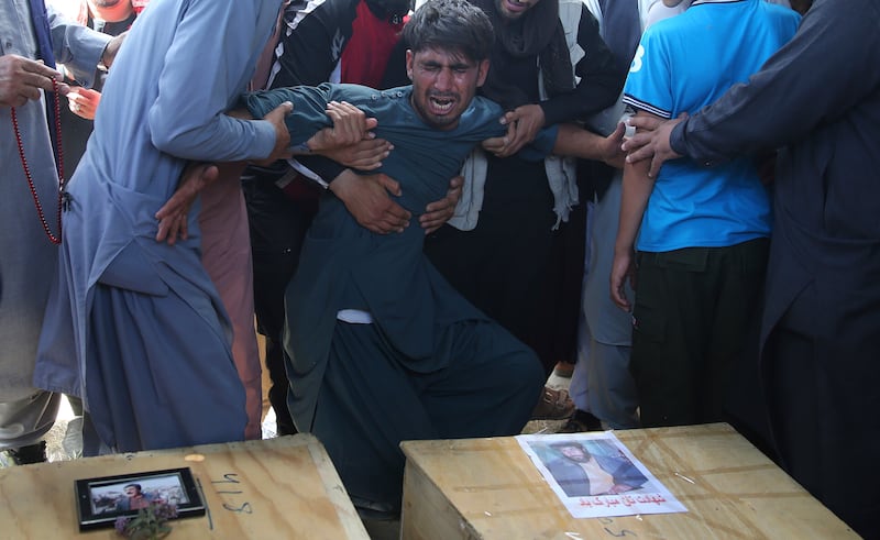 A relative wails near the coffins of victims of the Dubai City wedding hall bombing during a mass funeral in Kabul, Afghanistan, Sunday, Aug.18, 2019. The deadly bombing at the wedding in Afghanistan’s capital late Saturday that killed dozens of people wa