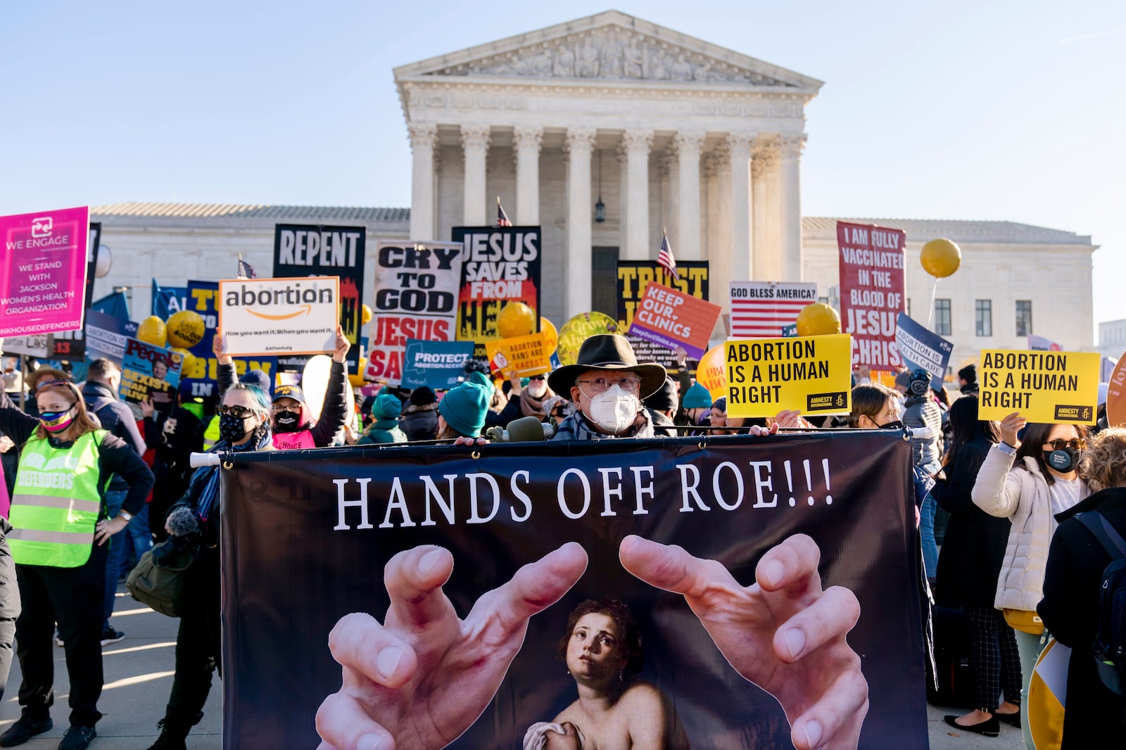 Stephen Parlato of Boulder, Colo., holds a sign that reads “Hands Off Roe!!!” as abortion rights advocates and anti-abortion protesters demonstrate in front of the U.S. Supreme Court.