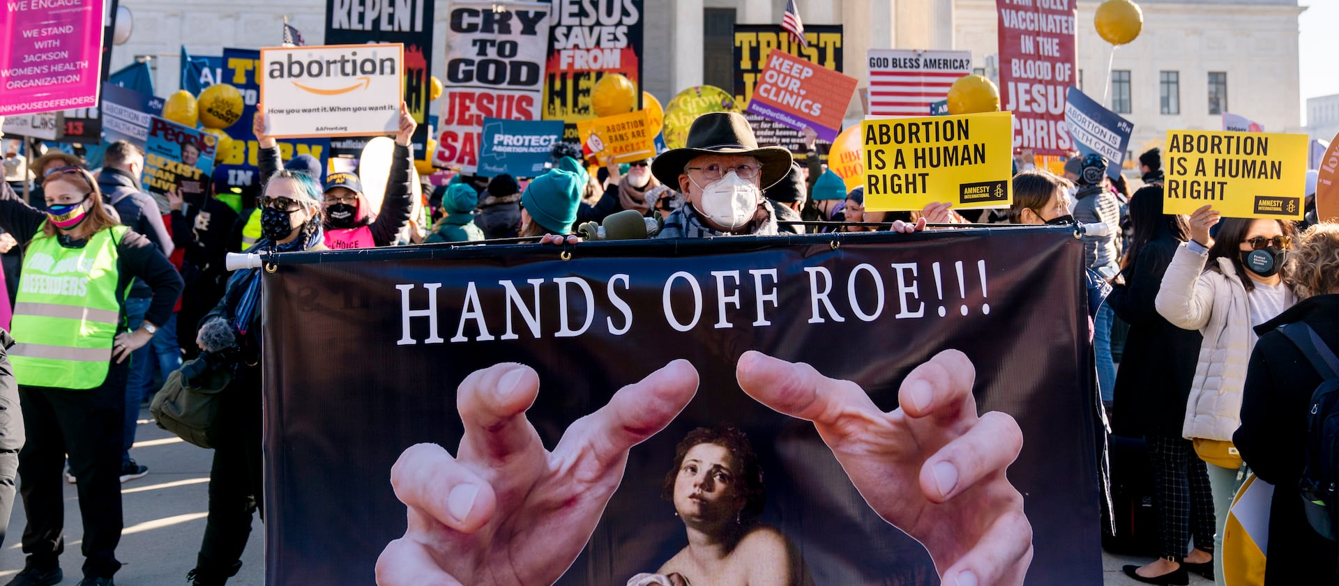 Stephen Parlato of Boulder, Colo., holds a sign that reads “Hands Off Roe!!!” as abortion rights advocates and anti-abortion protesters demonstrate in front of the U.S. Supreme Court.