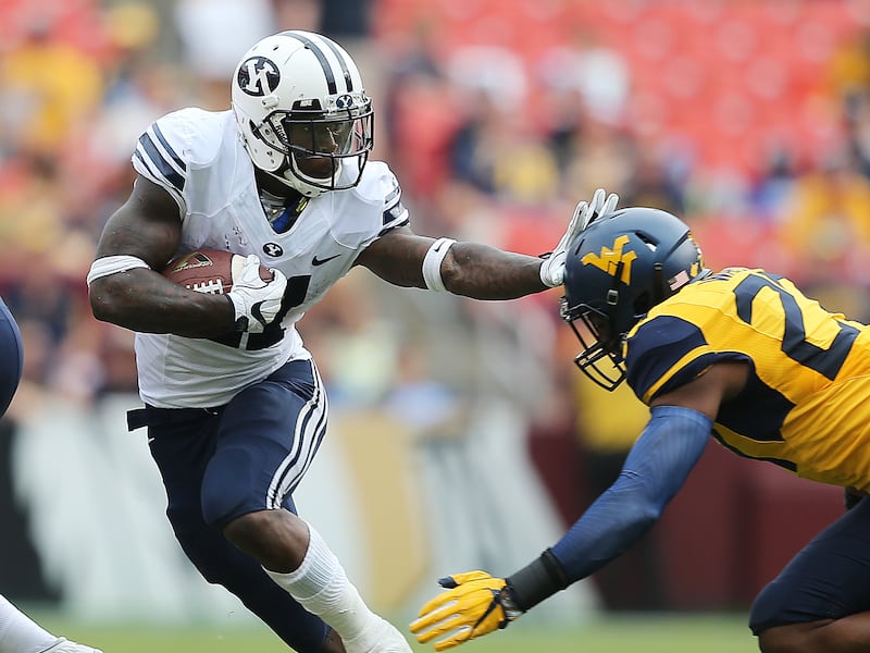 BYU’s Jamaal Williams stiff-arms a West Virginia player. If the Big 12 chooses to expand and BYU were to accept an offer, BYU and West Virginia would become conference rivals.