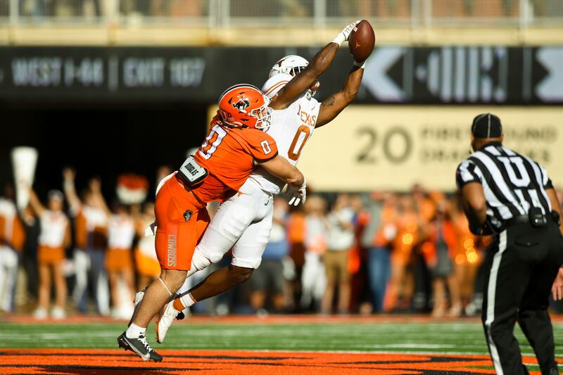 Oklahoma State linebacker Mason Cobb, left, holds on to Texas tight end Ja’Tavion Sanders who catches a pass during a college football game Saturday, Oct. 22, 2022, in Stillwater, Okla.