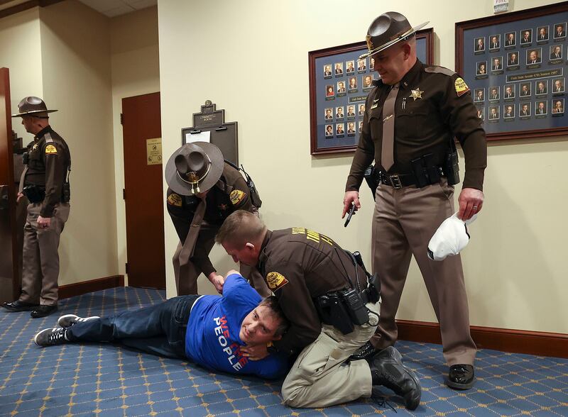 Utah Highway Patrol troopers take a man into custody for violating committee meeting rules at the state Legislature.