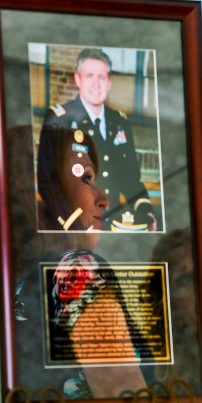 Jennie Taylor is reflected in a photograph of her husband, Maj. Brent Taylor during a dedication ceremony for the newly renamed Major Brent Taylor Vet Center Outstation in North Ogden on Monday, June 10, 2019. Brent Taylor was killed while serving in the