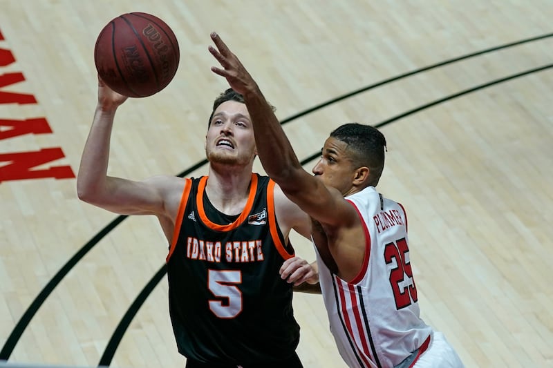 Utah guard Alfonso Plummer (25) and Idaho State guard Austin Smellie (5) battle for a rebound during the first half of an NCAA college basketball game Tuesday, Dec. 8, 2020, in Salt Lake City.