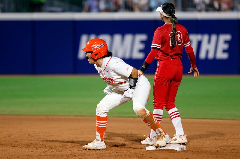 Oklahoma State’s Taylor Tuck, left, celebrates after a double next to Utah’s Aliya Belarde during the second inning of an NCAA softball Women’s College World Series game Friday, June 2, 2023, in Oklahoma City. (AP Photo/Nate Billings)