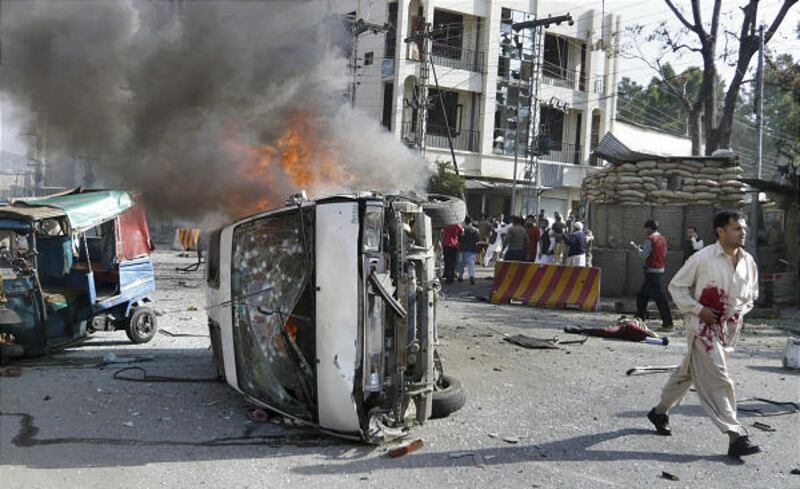An injured man walks away from a burning vehicle at the site of suicide bombing in Saidu Sharif, a town of Pakistan's Swat Valley, Saturday.