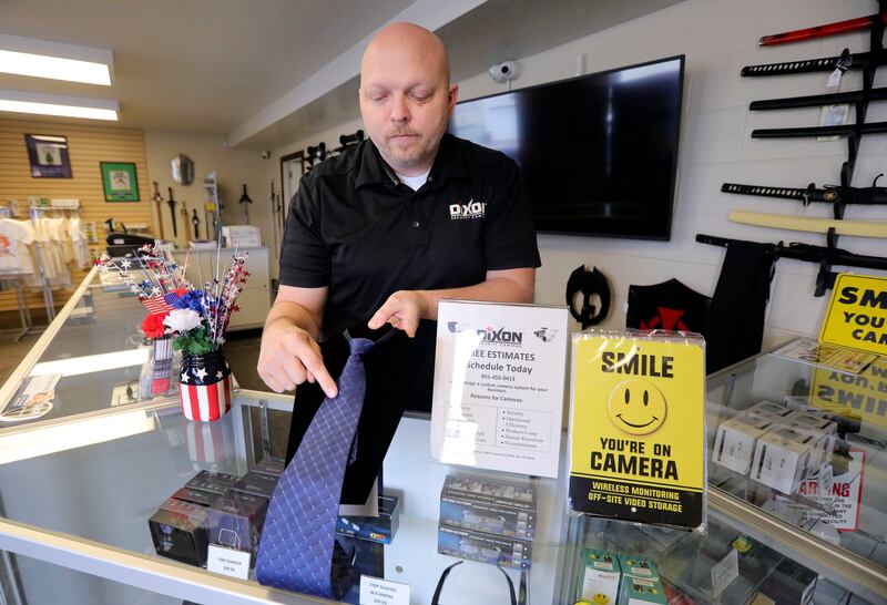 Thal Dixon points out where a spy camera is hidden in a necktie at Dixon Security Cameras in South Salt Lake on Tuesday, March 12, 2019.