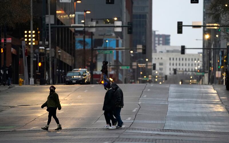 Pedestrians wear masks while crossing an empty road at the intersection of Market Street and 15th Avenue during the evening rush hour Monday, Dec. 28, 2020, in downtown Denver.