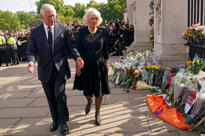 King Charles III and Queen Camilla look at floral tributes at Buckingham Palace following the death of Queen Elizabeth II.