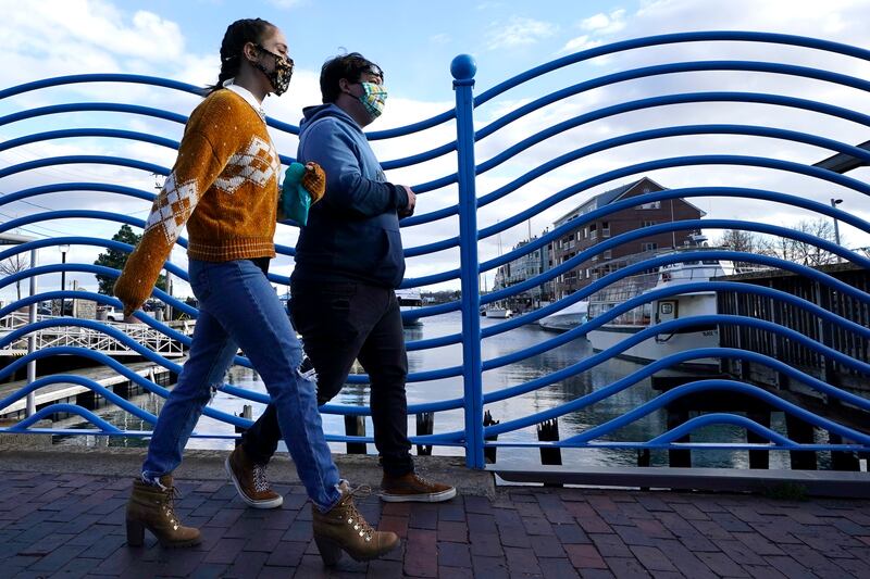 Pedestrians wear face coverings to help prevent the spread of coronavirus, Tuesday, Nov. 17, 2020, in Portland, Maine.