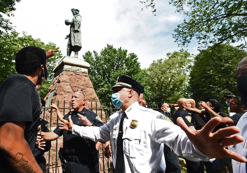 A man at left points to the statue of Christopher Columbus as police hold the crowd back before the statue was removed from Wooster Square Park, in New Haven, Conn. Disputes over what to do with statues of Christopher Columbus in Connecticut have resulted in both civil and criminal complaints.