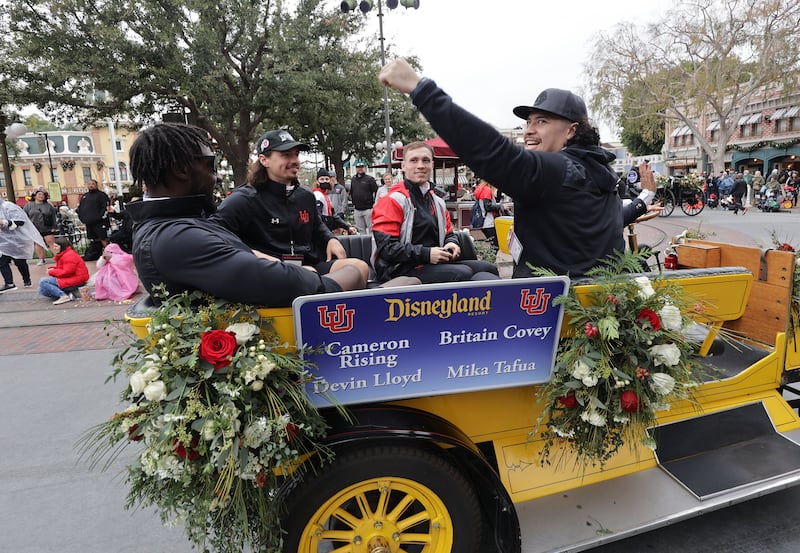 Utah Utes linebacker Devin Lloyd, Utah Utes quarterback Cameron Rising, Utah Utes wide receiver Britain Covey and Utah Utes defensive end Mika Tafua wave out of a car to fans during a parade