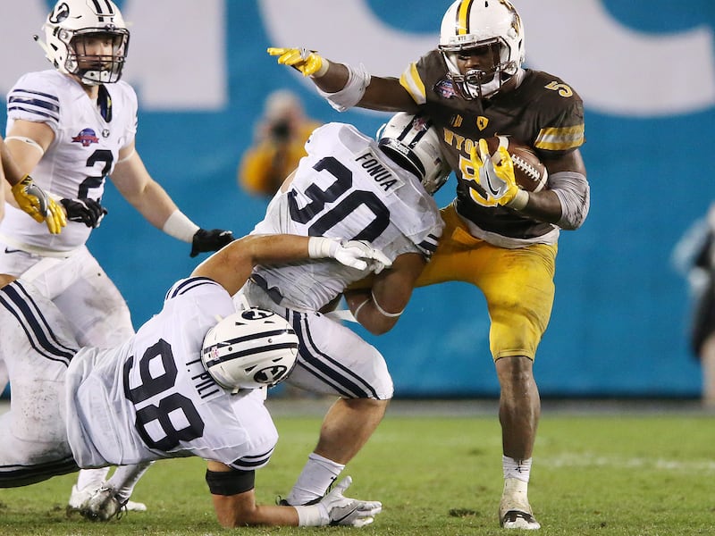 The Brigham Young Cougars’ defense tackle Wyoming Cowboys running back Brian Hill (5) during the Poinsettia Bowl in San Diego on Wednesday, Dec. 21, 2016. BYU won 24-21.
