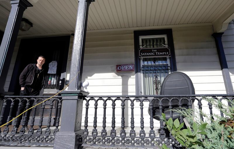 In this Oct. 24, 2016 photo, Lucien Greaves stands on the porch of the recently opened international headquarters of the Satanic Temple in Salem, Mass. The Satanic Temple is waging religious battles along a variety of fronts nationwide, and its co-founder