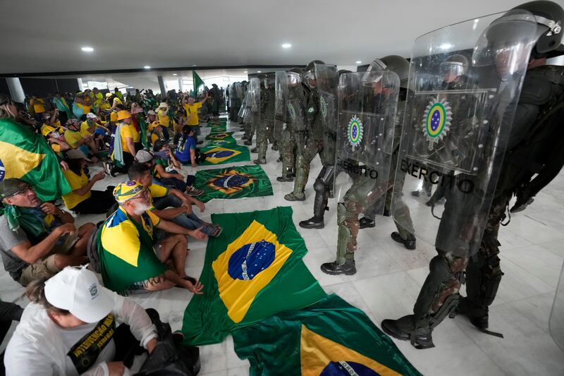 Protesters, supporters of Brazil’s former President Jair Bolsonaro, sit in front of police after inside Planalto Palace after storming it, in Brasilia, Brazil, Sunday, Jan. 8, 2023. Planalto is the official workplace of the president of Brazil.
