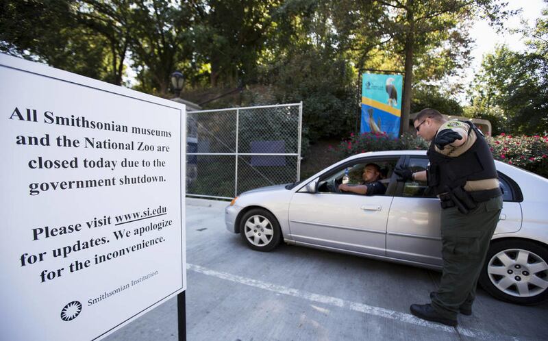 National Zoological Park Police Officer Will Jones directs visitor Miguel Miranda and his family of Mexico at the entrance of the Smithsonian National Zoological Park in Washington, Tuesday, Oct. 1, 2013, as the zoo is closed due to the government shutdow