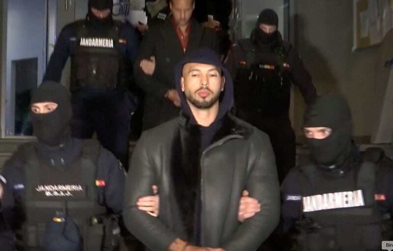 Social media personality Andrew Tate is led away by police north of Bucharest, Romania, on Thursday, Dec. 29, 2022.