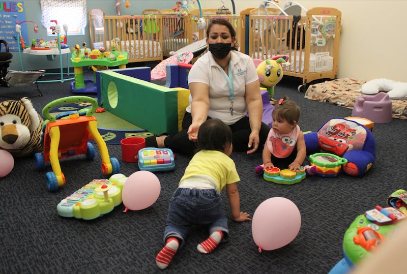 This May 4, 2021, image shows teacher Graciela Olague-Barrios working with infants at Cuidando Los Ninos in Albuquerque, N.M.