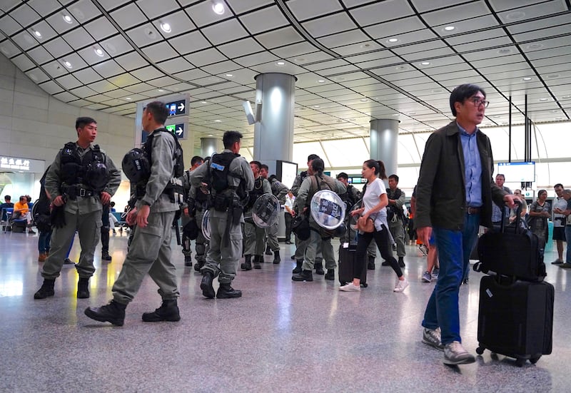 Riot police stand guard at the airport express central station in downtown Hong Kong, Saturday, Sept. 7, 2019. Hong Kong authorities were limiting airport transport services and controlling access to terminals Saturday as they braced for a second weekend of disruption following overnight demonstrations that turned violent. (AP Photo/Vincent Yu)