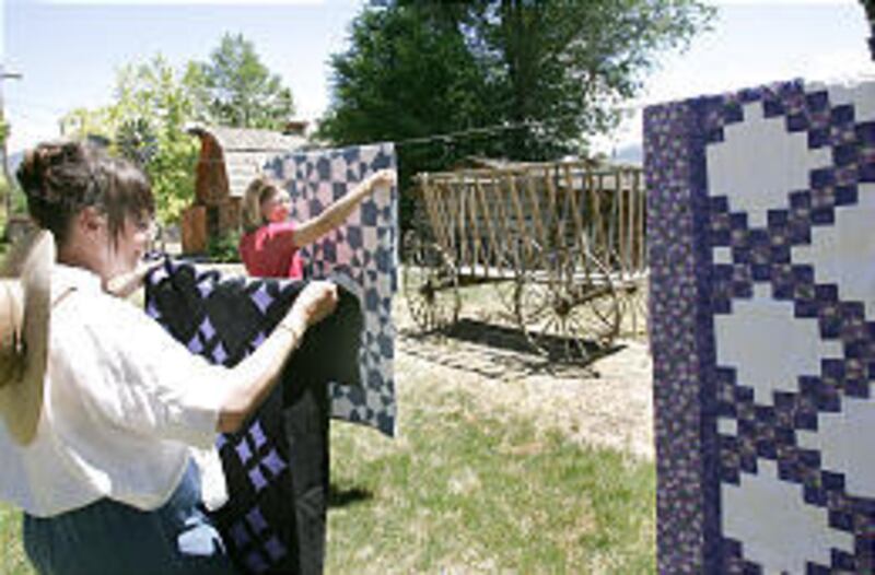 Elaine Jones-Hughes, in front, helps Shauna Warnick hang quilts for display at museum in Spanish Fork.