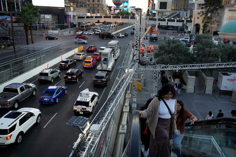 Pedestrians take an escalator along the Las Vegas Strip beside fencing installed ahead of the Las Vegas Grand Prix on Nov. 10, 2023