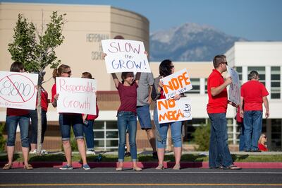 Protesters hold signs opposing the Olympia Hills development proposal before a town hall meeting in Herriman High School on Thursday, June 14, 2018. Many members of the community voiced concern about the high density of the development, which would suppor