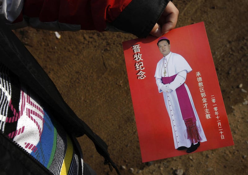 In this file photo taken on Nov. 20, 2010, a village boy shows a leaflet with picture of Bishop Guo Jincai, which he received from a worshiper after the bishop ordination ceremony at the Pingquan Church in Chengde city, northeastern Hebei province, China.
