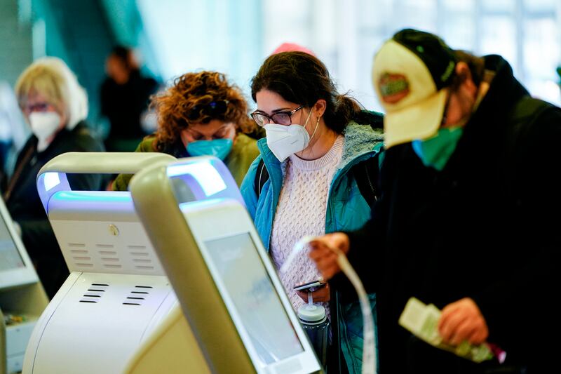 Travelers wearing protective masks check in at the Philadelphia International Airport in Philadelphia on Tuesday, April 19, 2022.