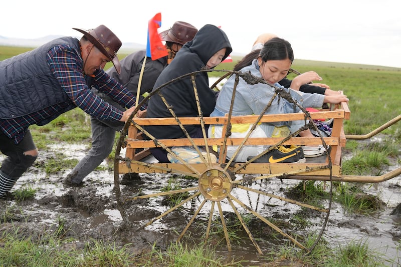 Latter-day Saint youth and leaders participate in trek, pushing a handcart through mud during the June 13 and 14, 2025, trek near Ulaanbatar, Mongolia.